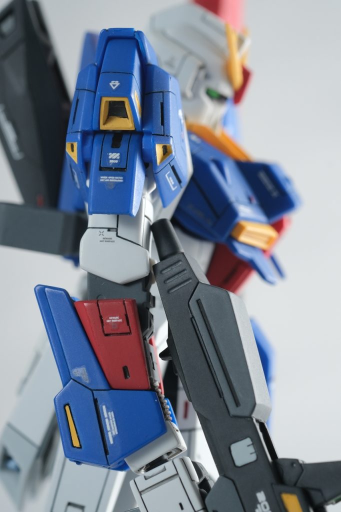 【腕】手首のグレネードランチャー発射口が緩くて、気が付くとフタが開いて弾頭が見えちゃってます。肩のスラスター(排気口?)の小さい方は、青いパーツに黄色を塗るという、ここも難関ポイントです。最初に筆塗りで黄色を先に塗ってしまったので、付属のシールでマスキングテープの代わりにして青色を吹きつけました。