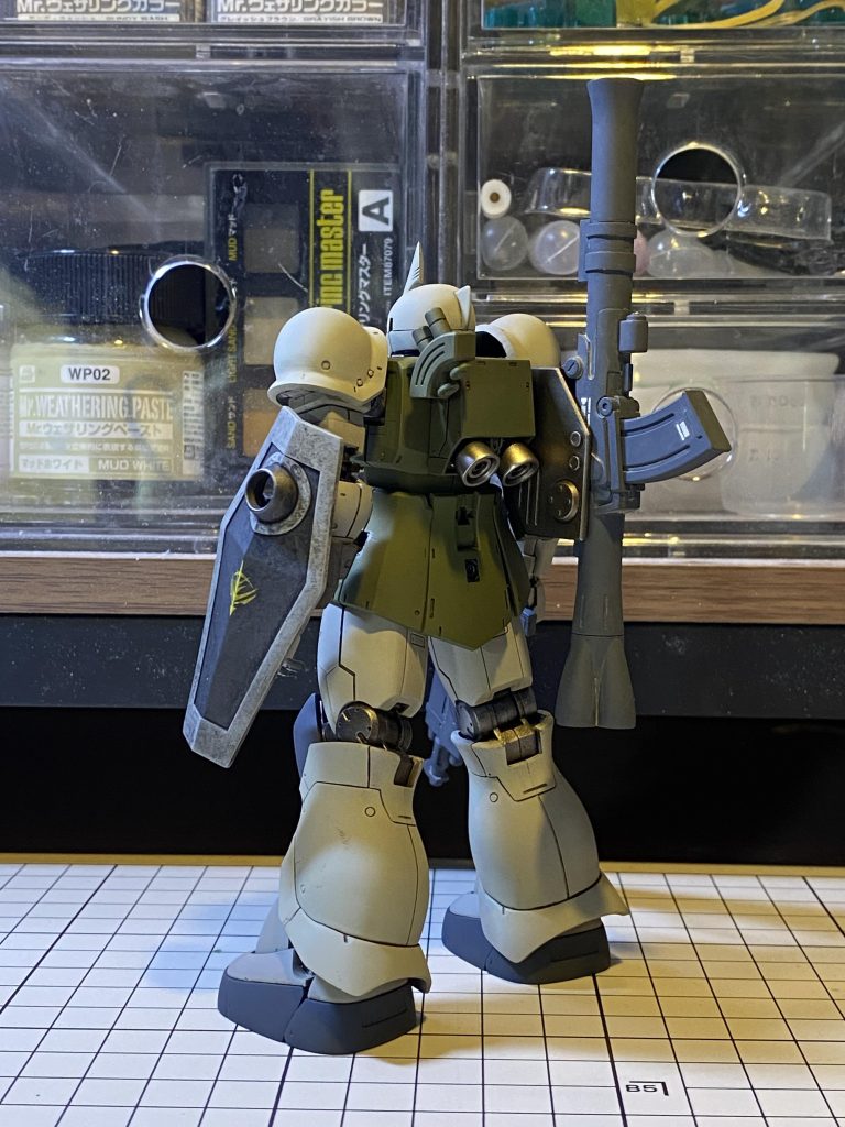 まずは小説版イメージ。本文中の「肩口にはバズーカが固定兵装で装備されていた他、煙幕弾の発射器も増設されているのが見て取れた。」との記述を参考に、ショートバレルのバズーカをビルダーズパーツから、バズーカ基部を旧MG量産型ゲルググ付属のキャノンパックから(不要な穴を埋めたり等しています)、スモークディスチャージャーをオリジンHGザクキャノンテストタイプから(肉抜き穴埋めし)持ってきて、それぞれ旧ザクのランドセルに元々あるハードポイントへ、3㎜ランナーを介して接続しました。バズーカは、写真のように基部から折りたたむことができます。