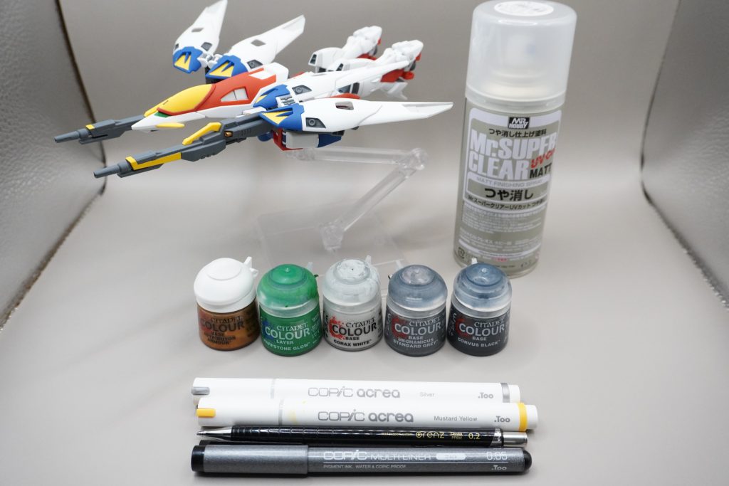 「簡単仕上げ」と一口に言っても色々あると思いますが、今回は以下の作業で実施しました。①アンテナの鋭利化②部分塗装③スミ入れ④トップコート(つや消し)今回使用した塗料などの紹介です。●部分塗装に使用 シタデルカラー(水性塗料) ・ベース RETRIBUTER ARMORD(ゴールド) ・ベース CORAX WHITE(ライトグレー) ・ベース MECHANICUS STANDAED GRAY(グレー) ・ベース CORVUS BLACK(黒) ・レイヤー WARPSTONE GLOW(緑) ・レイヤー EVIL SUNZ SCARLET(明るめの赤)←写真に載せ忘れました コピックアクレア(カラーペン、水性) ・Mustard Yellow(黄) ・Silver(銀) コピックマルチライナー0.05(黒ペン、水性)●スミ入れに使用 Orenz 0.2mm(シャーペン、HB芯使用)●トップコート(≒仕上げ用スプレー) Mr.スーパークリアーUVカットつや消し(ラッカー系)道具はそれぞれ、別のものに置き換えてもらっても全く問題ありません。個人的に使いやすいもので構成しています(つや消しスプレーはテキトー)