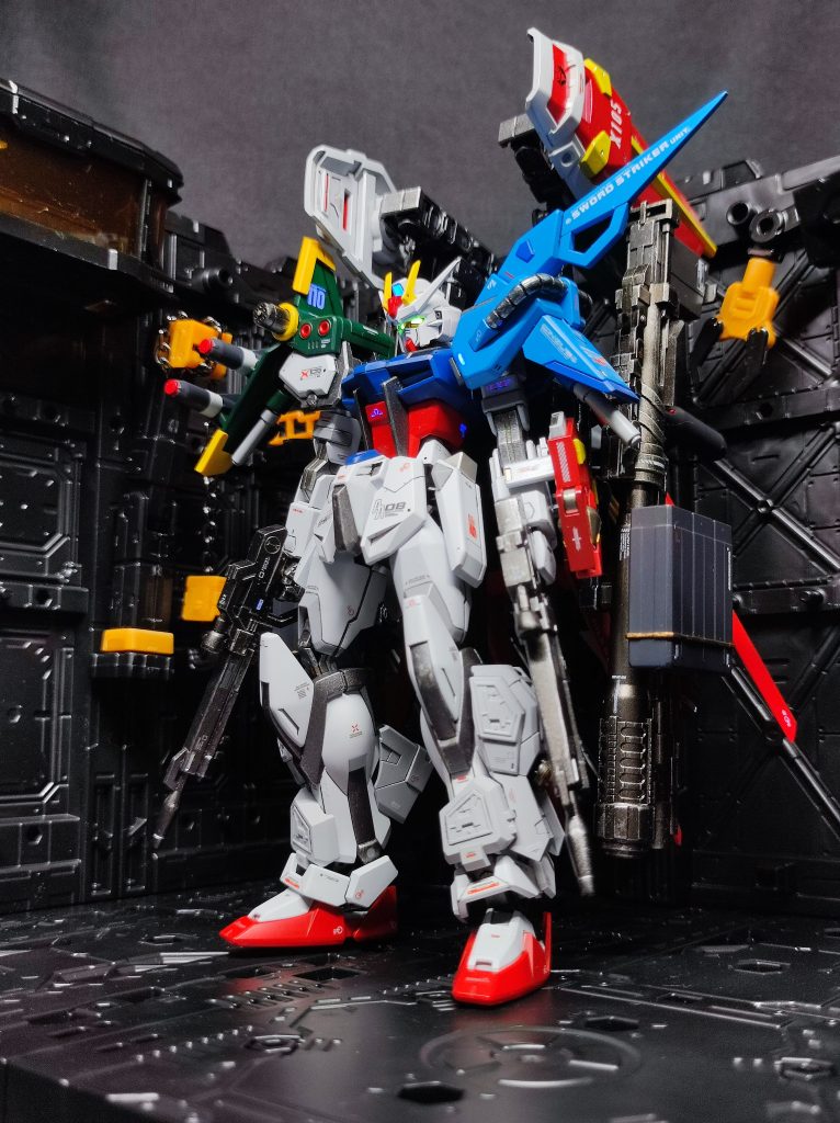 山田化学格納庫&素立ち。(一番ポージングに苦戦しました・・・背面重すぎ！)色分けについては基本的にキットと同系統にしてますが、そのまま過ぎるのもあれなのでソードのシールドはエールのものと同じ感じの配色に変更しました。ソードのシールドはクロー部の接続部品が小さくて無くしてしまったため、UVレジンで複製したのですが取り付け時に強度不足で割れてしまったため再複製してから諦めて接着したのでパンツァーアイゼンは射出不可です（ 泣）気になるところはシャープ化しましたが、基本つや消し寄りのトップコートなので面倒なヒケ処理は省略。EGグラスフェザーは、そのままだと当然ですがストライクの丸みのある？脚部と干渉するのでカットやらヤスリやらをして取り付け。パッと見は良い感じに付けれました。 