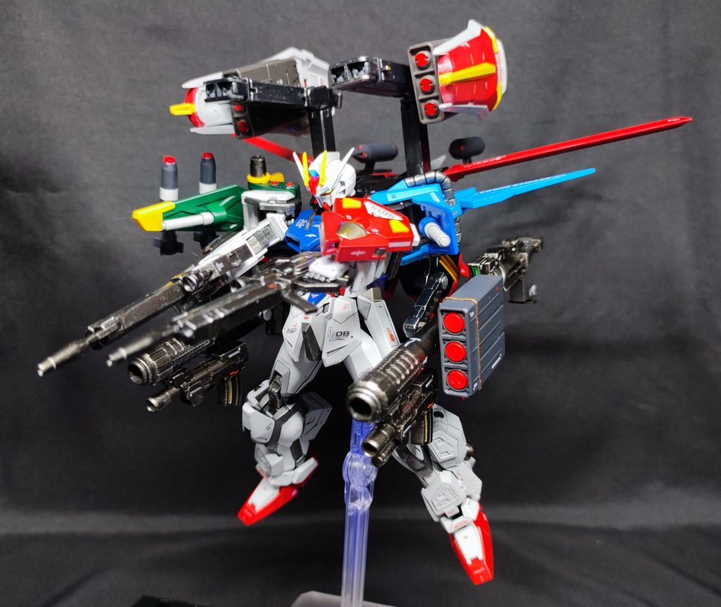 会敵直後、一斉発射！フォートレスストライカーは、対ビームシールドを増設することで敵ビーム兵器に対する生存性を向上させつつ、①非PS装甲に対し依然として有効②ビーム兵器と異なりバッテリーを直接消費しない③大気による減衰の影響が少ないと大気圏内で量産機を相手にする上で未だ有効である実弾兵装を多数搭載することにより、生存性と継戦能力の強化を図った急造の強化プランである。