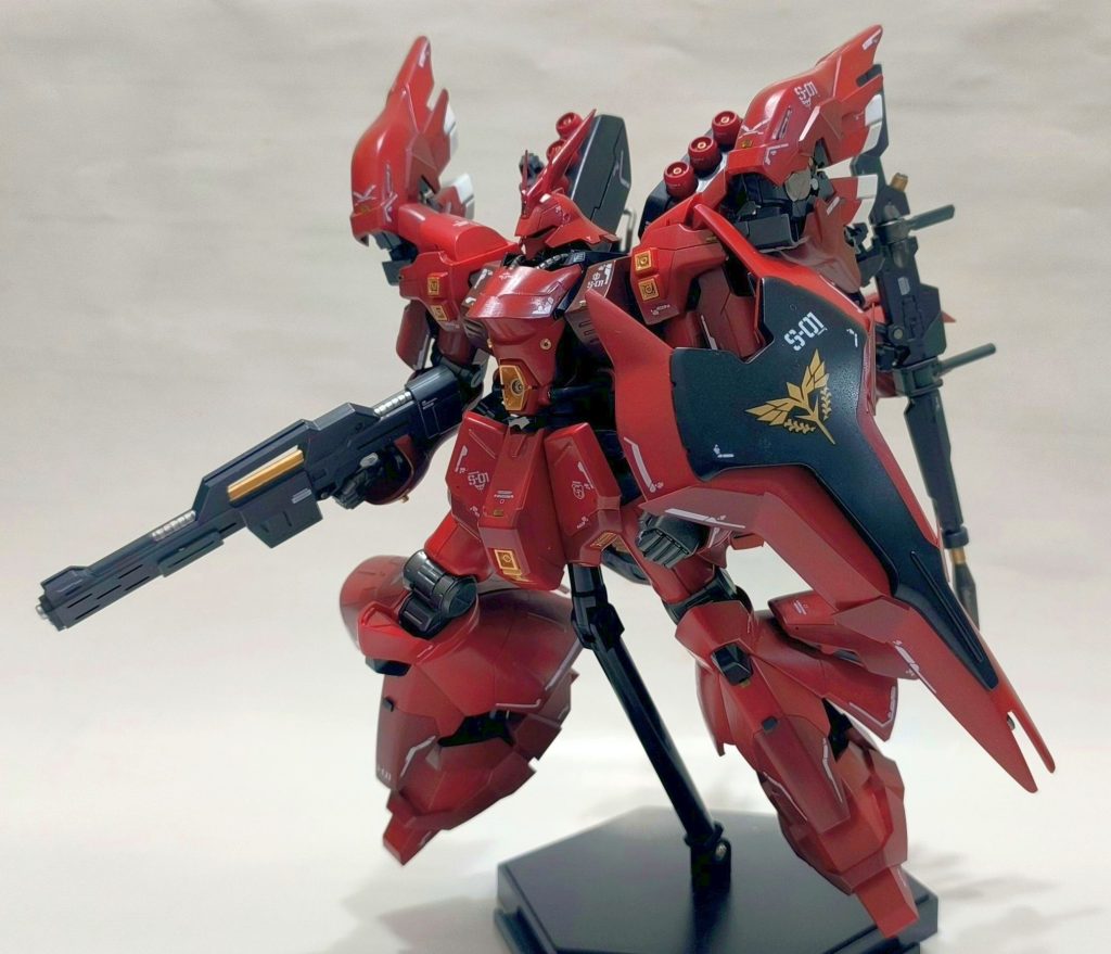 素のサザビーから大きくイメージは変えず、シナンジュのスラスターやパーツ類をもとからそういうデザインであったよう配置することに気を配りました。シナンジュの大きな特徴のひとつである、背面の翼型推力偏向スラスターは、あれこれ配置を変えながら検討した結果、ファンネルとケンカしない位置である肩部へ設置。これがしっくりきました。その他工作としては、・スジボリと、色分け・プラバンによる意匠変更(盾と、胸部など)・脚部スカートのカット・メタル風ビーズ追加・グリーンポイント追加・水転写デカールを施工しています。プロポーションそのものはいじっていません。塗装はいつもの水性ホビーカラー筆塗と、リアルタッチマーカー、ガンダムマーカーEXメタリックです。妄想ストーリーとしては、アクシズ・ショックを奇跡的に生き延びたシャアの専用機体として、UC0096年の技術レベルで再設計されたもの、というところでしょうか。