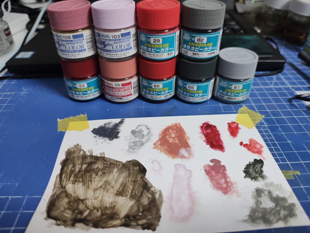 製作途中の写真が何もなかったので、使用後の紙パレットの写真と共に色レシピ。メカサフヘビィからの水性ホビーカラーの清水式筆塗りです。濃赤: あずき色 > ジャスティスピンクピンク: シャア専用機ピンク > ストライクルージュピンクランドセル: モンザレッド  > サーモンピンク胸肘膝靴: RLM74グレーグリーン  > 軍艦色1関節: メカサフヘビィのまま武器: メカサフヘビィをほぼ残し > 軍艦色1と明灰白色1若干エナメルダーグレーチッピング>半光沢トップコート> ダークブランウォッシング付属のデカールは最後に貼って、貼った場所の色で馴染ませてデカールの上だけウォッシングしなおし。できるだけデカールの段差にダークブラウンが残らないように。パレットは基本的に上下で上1色目、下2色目。左上隅がチッピングのダークグレーで、その下の一番広い茶色がウォッシングのダークブラウン。並べた塗料とパレット上の並びが全然揃ってないですが。