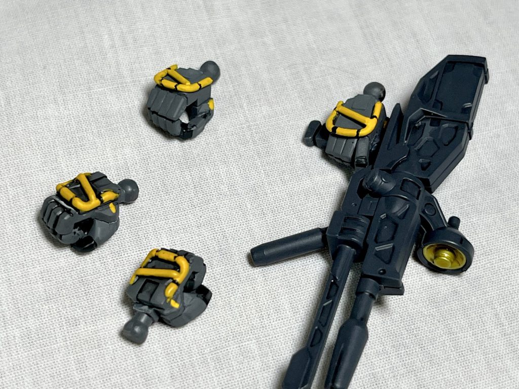 小改造のハンドパーツになります。まずは元々のキットに付属する握り手兼武器持ち手の手の甲を拝借し、HGジムカスタムなどに付属する握り手とフィットするように削って接着しています。親指部分は太く感じたのでニッパーで切り離して形を整えています。やはり握り手は欲しいので製作しました。ライフル持ち手とサーベル持ち手も他のキットから流用しています。手の甲は1.0mmの真鍮線を加工して再現しています。