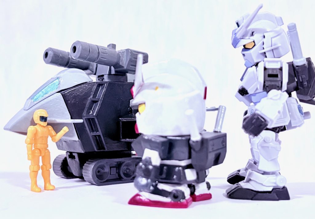 「あぶ刑事ガンダム」でもGファイターは物語のカギを握る存在で、一度目はマクベリィ少佐のGファイターとユージのＧ3ガンダムがＧアーマー形態でドズルのビグザムを翻弄し、ガンダムに分離したところでビグザムを倒した。二度目はゼクノヴァを解析したテム・レイが小型化したオメガサイコミュを搭載した機体が登場。※ここからはジークアクスやTFネタを含みます。ユージ（G3ガンダム）「なんなんだ、このビックリドッキリメカは⁉」トオル（左のノーマルスーツ）「鷹山先輩と大下先輩がガンダムの世界でも派手に暴れたって事を聞いて、テム・レイ博士と一緒に用意したんですよ。」タカ（黒いガンダム）「相変わらず気が利くな」トオル「一生ついていくって言ったじゃないですか！！」ユージ「で、どうやってキラキラの向こう側へ行くんだ？」テム・レイ「それは私が話そう！！」 