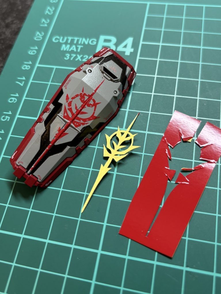 盾のジオン紋章はテトロンシールだと凹凸が気になっちゃうのでハセガワの赤フィニッシュ🟥で頑張ってみました😌🟥の台紙の裏にテトロン〜を貼り、それをガイドにして切ってから盾に貼ってます。最後に下地を傷付けない様にナイフでシートだけ引っ掛けて小さくむしると完成!