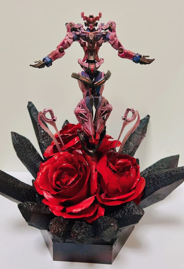 ジークアクスを覆っている黒い結晶のようなものには、セリアのポリスチレンフォームを使用しています。また、敢えて「発泡スチロール禁止」のスプレーを使用することで丁度いい具合にスチロール表面部分を溶かし、得体の知れないリアル感を表現しています。 また、薔薇と土台は、それぞれキャンドゥに販売されていた「ストーン調ヘキサゴントレー」というものと、「インテリアフラワー ローズ」を使用し、どちらも塗装しています。