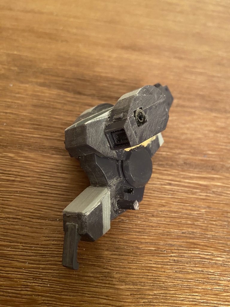 前述の胸部・腰部の改修点が見て取れるかと思います。胸部左右のブロックは上半分のパーツを小型化(うっすらカット跡が見えます)するとともに、ダクトを薄く加工。元々ダクトと胸部中央前面がほぼ平行になるような角度でしたが、一旦切り離しやや下向きになるよう再接着。本来背部(首後ろ)の天面は元の胸部中央の天面が途中で少し折れて下がる形でしたが、胸部天面の傾斜を起こすとともに背部はほぼ面一に。