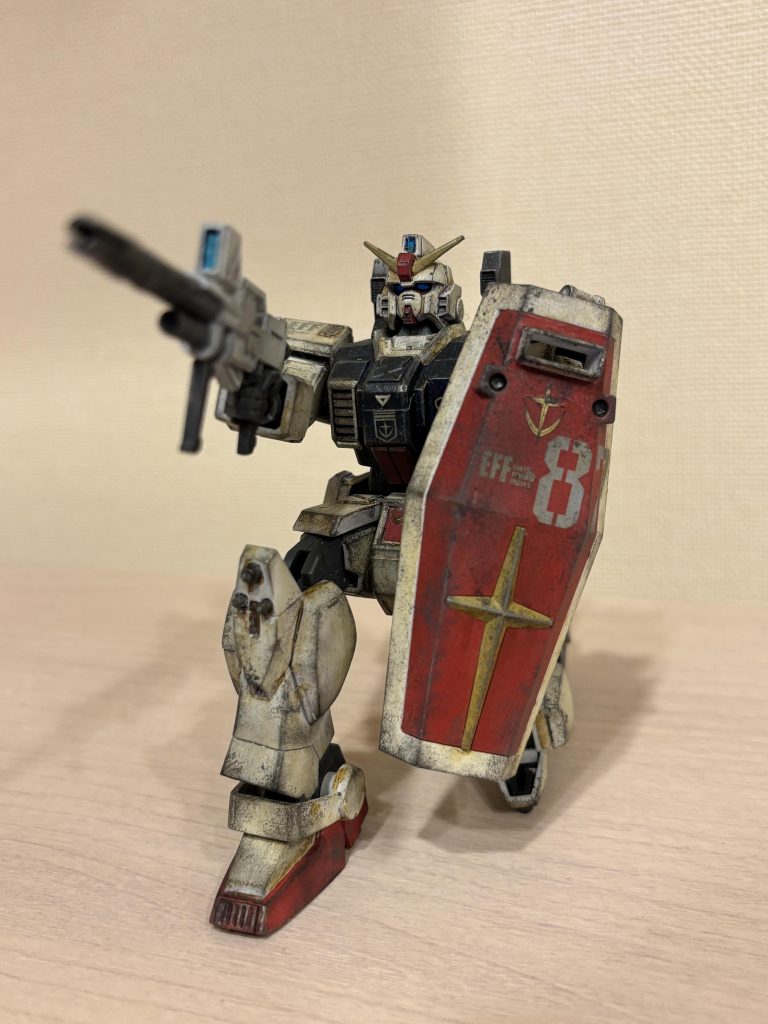 中古のジャンク品を購入したので、ビームライフルしか持っていませんでした……なので、ビームライフルの試験機、みたいな適当な妄想をしています(gundam-kao10)  処分してしまいましたが、旧HGUC版も持っていたので、もともと稼働の良さは分かっていたのですが、リバイブ版の稼働域の改善にはビックリしました。戦闘中、屈んだり、銃を構えたりのポーズがすごくカッコよく決まります。 次の主役機は、ちょっと稼働が落ちるので、カッコいい画作りに苦労しそうです。 カラーは白:灰色9号青:ブルーインパルスカラー+青竹色少々赤:デスティニーレッド黄:サンドイエロー?関節部等:焼鉄色カメラアイ:青竹色+蛍光ブルー(ガイアカラー)です。当時覚えたてのスポンジでのチッピング(グレー)でウェザリングを施しています。仕上げに、ウェザリングマスターのグレーを全身にまぶし、水性つや消しスプレーを塗布しています。 他の皆さんの作品と比べると明らかにやりすぎで、特に第1話時点では1度も戦闘していないのに、なんであんなに汚いのか、という感じです(gundam-kao10)