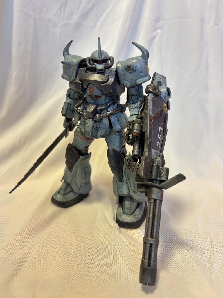 MS-07B3 グフカスタム アーサー・クレイグ大尉専用機で、オデッサの前衛拠点を守備するクレイグ中隊の指揮官機です。特別な高性能化は施されていません。 地球降下作戦から、東欧制圧までの戦功が認められて受領した機体です。 色は青:RLM65ライトブルー灰色:ガンダムルブリスグレーパイプや武器:焼鉄色です。灰色に見えますが、一応青なんです。 あと、黒下地に、筆の代わりにスポンジで着色し、最初からウェザリングぽく見えるようにしてみました。仕上げにチッピングとウェザリングマスターも少々施しています。