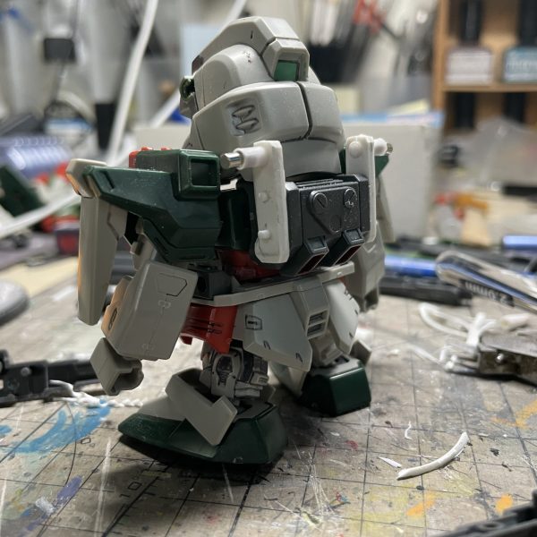 一年前、SDヴェルデバスターガンダムをベースにSDバスターガンダムへ改造した際の工程記録を公開します。第二弾は「胴体」と「バックパック」の改造工程です。  【胴体改造】1. プラ板を二重積層し胸部装甲の形状を再現 2. 元キットの胴体赤パーツからコクピット部のみを残して切削3. 切削パーツにプラ板を貼り付け、胴体との組み合わせを調整  【バックパック改造】バスターガンダム特有の可動アームについて：  腰の可動制限＆SDスケール再現難のため、アーム上部形状のみをバックパックに直接固定、武装接続部に磁石を埋め込み、着脱式の武装を実現「胴体とバックパックの換装完了！可動制限を回避しつつ特徴を再現」（7枚目）