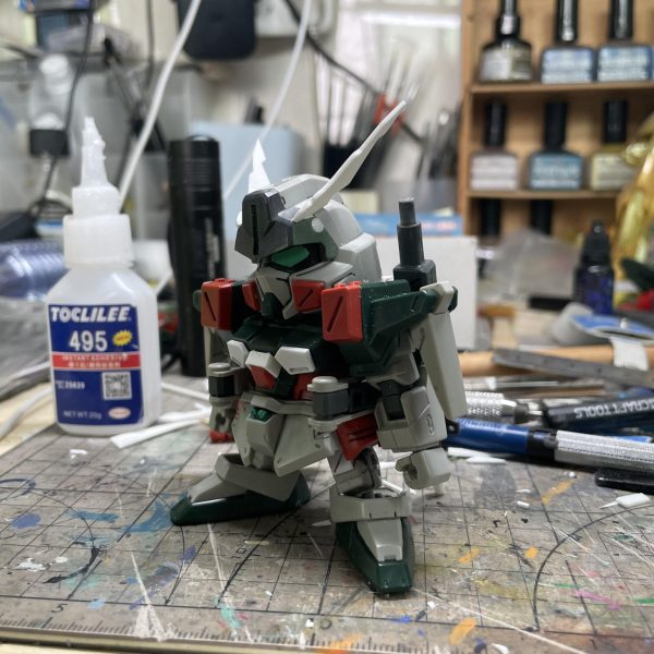 一年前、SDヴェルデバスターガンダムをベースにSDバスターガンダムへ改造した際の工程記録を公開します。最終章は「頭部」の改造工程です。【頭部改造】1. アンテナの制作 設定資料を基にアンテナ形状を確定し、プラ板で作り、そして頭部緑パーツに矩形スロットを切削し、アンテナを埋め込み  2. 可動式防弾装甲取り外し後の処理可動式防弾装甲取り外しで、露出した緑パーツの円孔をプラ棒で埋め戻し3. バスターガンダム特有のセンサー防弾装甲再現    設定画を参照し防弾装甲の造型をSD頭部サイズに最適化（幅調整）、そしてプラ板で制作。  4. 頭部改造完成  センサー防弾装甲を組み込み、頭部の変換を完了【完結】  これをもって、SDヴェルデバスターガンダムからSDバスターガンダムへの改造は全て完了いたしました！ （3枚目）
