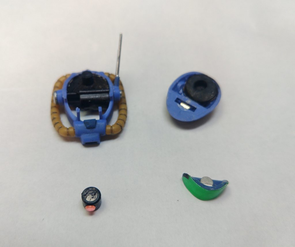 頭部を幅詰めで上下分割した際、継ぎ目を消さないで分割線として、バイザーの上にネオジム磁石を仕込んでいます。これによってモノアイが可動します。使わない方のパーツは、紛失防止の意味で手持ちシールドの裏に仕込んだネオジム磁石に貼って収容できます。