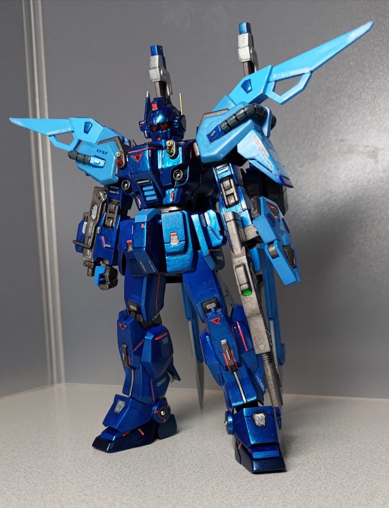 フロントショットです。肩アーマーをHGCEエールストライク(ジャンク品)に交換してソードストライカーを装備してます。また左手にはエールストライカーオプションに付属する90㎜対空散弾銃を持たせました。細かい改造箇所は下記の通り。首、胸、ひざ、足首の関節、脚部前面装甲にプラ板や棒を仕込んで1㎜ずつ延長。前腕部側面のシールド取り付け部を切り取って別の面に再接着。小型化した100㎜マシンガンを右手に、パンツァーアイゼンを左手にマウント。マシンガンの邪魔になるので右肩のみアーマーを一部切除。頭部左側面に真鍮線アンテナを増設。胸部バルカンにICピンソケットと100均の一分竹を埋め込み。アンクルガード側面にメタルボール埋め込み。散弾銃をリアスカートにマウントできるようにネオジム磁石を内蔵。脚部後面に余剰パーツとコトブキヤのM.S.G.を使ってスラスター増設。ソードストライカーのバックパックを、左側にもシュベルトゲベールをマウントするように改造。これをネオジム磁石とプラ板でBDのバックパックに後付け。さらに30MMオプションからテイルブレードを追加。さらにさらに対空小型ミサイルランチャーも追加。