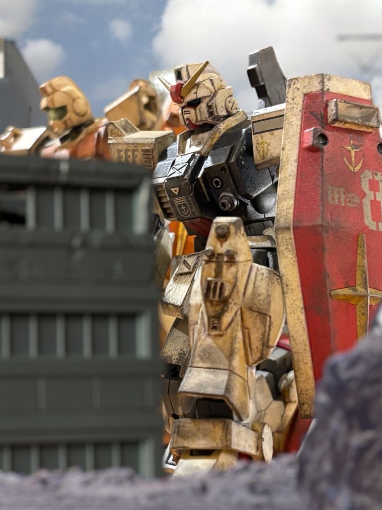 “ガンダム”出現の一報を受けた瞬間、アーサーは思わず椅子を蹴るように立ち上がった。 斥候のために、あちこちに放っていたワッパの一隊が持ち帰った情報だ。オデッサ市の北側の市街地に、遊撃隊と思しき連邦軍の戦力が布陣しているという。はっきりとは分からないが、歩兵隊と、戦車が1個小隊。そしてMSがおそらく2機。うち1機は、ブイ字アンテナに人の顔のようなツインアイを持っている。そして、機体は派手なトリコロールカラーだという。「間違いない、噂に聞く“ガンダム”だ。」アーサーは、柄にもなく興奮する。(俺は、そんなにやつと戦いたかったのか。)自嘲気味に内省するも、気持ちの昂ぶりを感じる。やはり、武人としての矜持がくすぶっているのか。 斥候の報告によれば、一応身を隠すようなそぶりも見えなくもないが、そこに布陣していることを隠していないのは明らかだ。罠だろうか。だとしても、やつを撃破するのは、この戦力では自分の仕事だろう。「よくやった。これ以上ない有益な情報だ。こいつらの相手はMSだ。他の兵は戦闘に参加するな。」覚悟が決まれば、作戦も決まったようなものだ。隊への指示を、オスカーに矢継ぎ早に伝える。「撤退する兵は西に大きく迂回させて、なるべく南側から宇宙港に入らせろ。ルーマニア方面から落ち延びてくる戦力もあるはずだ。可能な限り合流するようにも伝えろ。」「そちらのルートに罠をはっている、ということはありませんか。」「考えたが、恐らく可能性は低い。寡兵は連邦も同じと見える。」ここまでの逃避行を、まんまと成し遂げたのは、奇跡的に連邦の戦力と遭遇しなかったせいだ。作戦経路の立案に嗅覚を発揮するオスカーの力もある。しかしおそらく、全戦力を鉱山基地に向かわせているため、末端の戦場に振り分ける余力もないのだろう。 中隊の生き残り5機のうち、2機は念のため撤退部隊の直掩に付けるよう指示した。「オデッサ市に入ったら、適当なタイミングで機体は捨てて構わん。とにかく生き残れ。」弾薬も大して残っていない。会敵してもまともに戦えないかもしれない。ならば、会敵した瞬間、おとりがわりに捨ててしまってもいい。「対“ガンダム”決死隊は、わたしと、オスカーと、マイロだ。」最後にそれだけ告げると、2人を連れて外に出た。