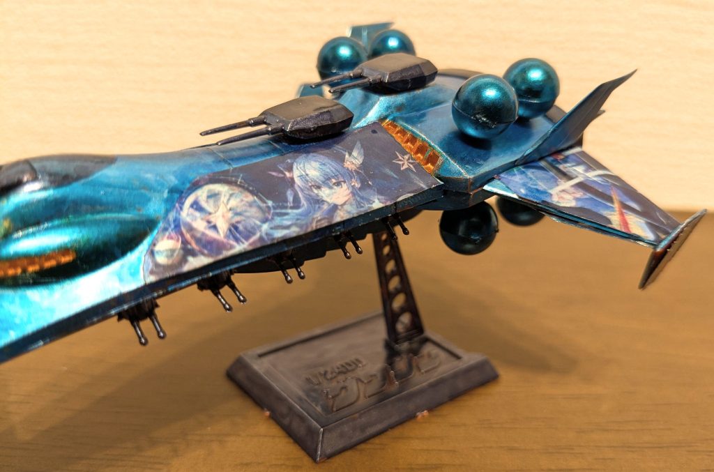 左舷側から1枚。本体色はメタリックブルー、ポイントになるようなエネルギータンク、艦底、ブリッジ周りはコスモメタブルー、銃座、バーニア周りはメタリックダークブルーの青系統3色と、ブリッジ、バーニア内部等はメタリックオレンジで塗装。星街すいせいイメージのカラーリングにしてみました。