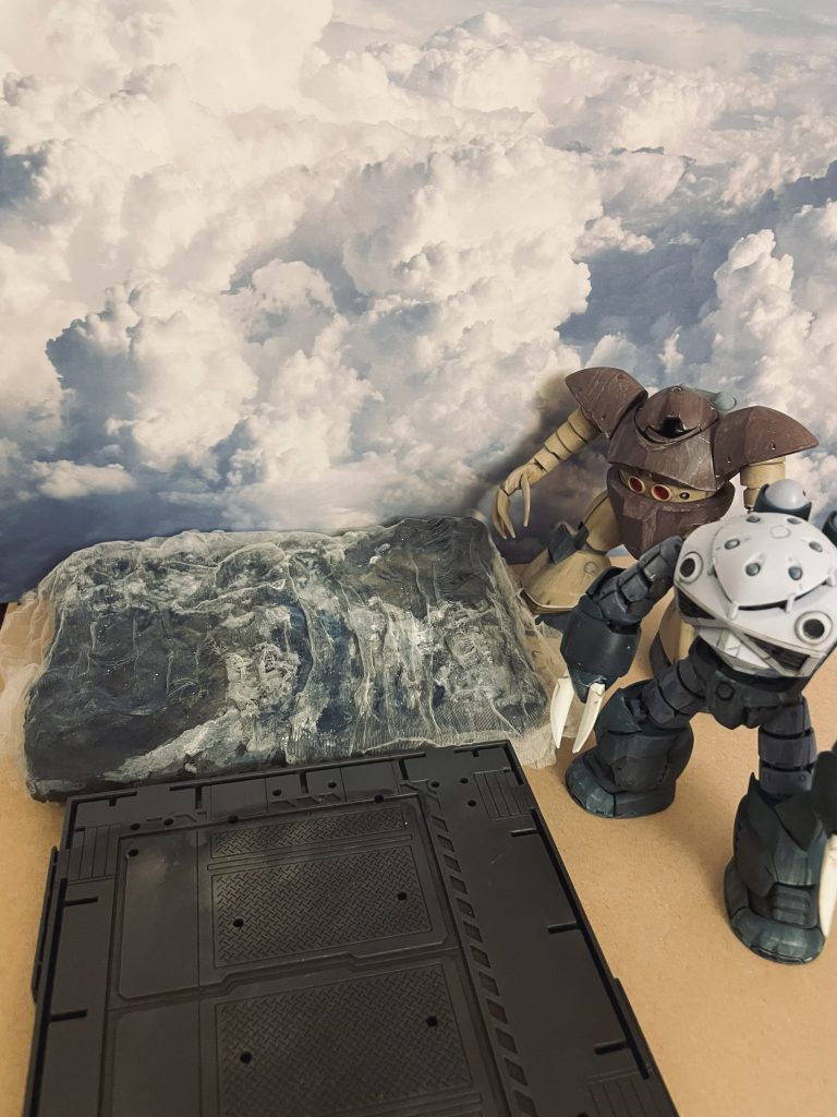 ジオラマ全景です。海面は粘土で表面を整えた後アクリルの青を塗布、乾燥後キッチンネットを被せて「うねり」を表現しようと試みました。波間の水飛沫を意図してガイアカラーのEx-フラットホワイトをまぶしています。黒くなっている部分に水柱を置くイメージです。