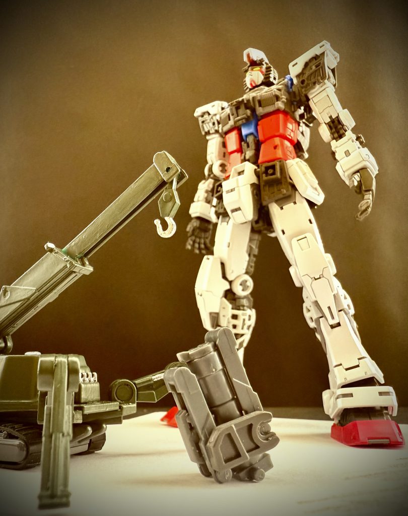 ※画像は再現映像 …しかし、その問題は割と呆気なく解決する。 モニター越しの会議の際だった。男が見ているモニターの向こう側の人物が、モニターの汚れを取ろうと手に取った物。モニター用のウェットティッシュ。…円柱状のケース上部からティッシュを抜き出す、「アレ」だ! 男は声を上げる。 円柱状のカートリッジケース内に、緩く渦を巻くように収められたフィルムは、ケース先端部よりガス圧によって少し押し出される。それならばRX-78の指先でもフィルムを摘むことが出来る。何度も重ねた実証の結果に男達は湧き上がる。その勢いのまま、男達は、カートリッジ式のユニットにした耐熱フィルムの収納の為、すでにほぼ完成していたRX-78の一部のデザイン変更を、軍上層部に打診したのである。 その部位は、腰、股間部。 手が届き易く、取り出し易い。取り出した後もすぐに機体前面に展開し易い場所。この、急とも言えるデザイン変更は、驚く程の速さで受理されると、数日後には、全ての部署に変更された仕様書、図面が渡された。 かくして、耐熱フィルムの収められた円柱状のカートリッジケースは、RX-78の腰部前面装甲、三つの装甲の真ん中、盛り上がった股間部の中に収められた。 …プロジェクトアールエックス