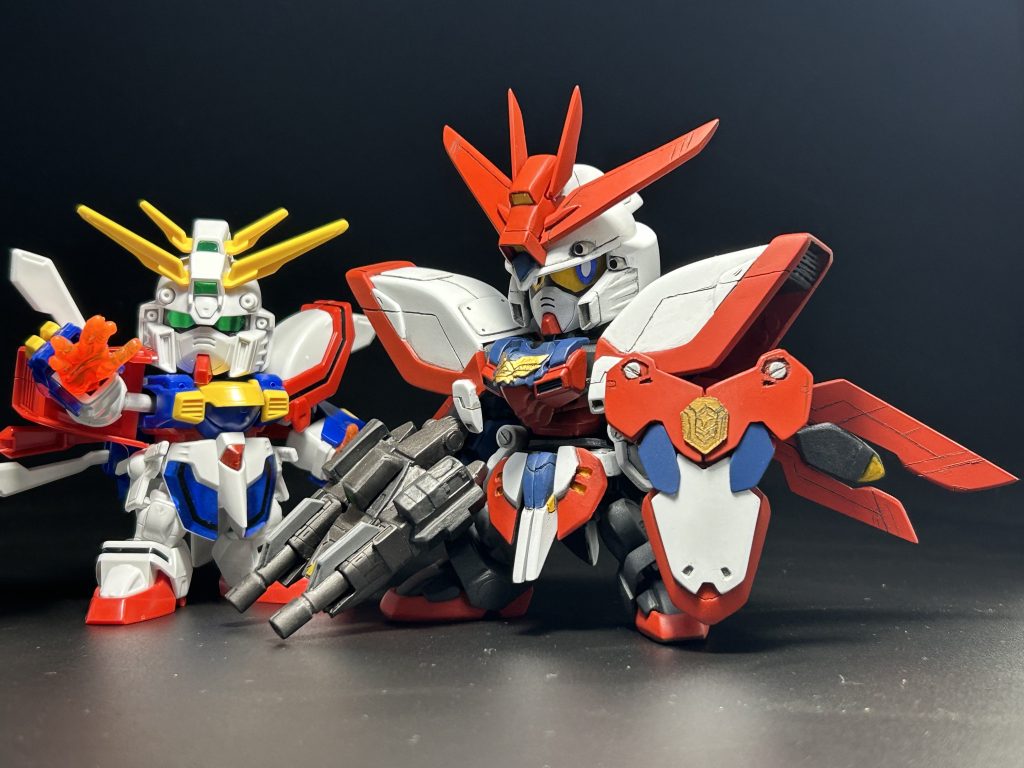 (後に中古屋で見つけた)改造元のゴッドとツーショット。と言っても、ほとんど別パーツになっちゃってますが。今回特にこだわった部分は頭で、箱絵の丸顔に近づける為に2mm横に延長したり、瞳をマグネットで作って目線を変えられる様にしたり、目線を変え易くする為ヘルメットを脱げる様にしたり(脱ぎません)、バルカンを金属パーツに変えたりなど色々弄ってます。SDガンダムは顔が命!という誰かの名言が心に刺さったのです…