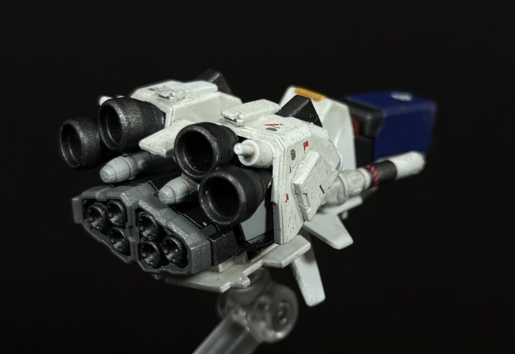 [コアファイター]本機はバックパックに大口径スラスターを増設した関係で、原型機に搭載されていたウィング展開機能はオミットされているのだが、コアファイターを用いた脱出機構自体は搭載されている。推進力の増加によって機動力は向上することとなったが、構造上ウィング部分の小型化を余儀なくされたため、大気圏内での安定性がやや低下することとなった。