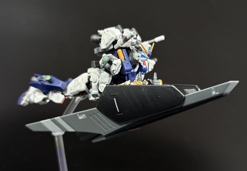 [SFS及び大気圏突入補助機能]シールド裏面にはツィマッド社の開発した土星エンジンを用いた大型ブースターが双発で搭載されており、大推力を利用して簡易的なSFSとして運用することも可能となっている。また、シャトルの底面を転用したシールドであることもあり耐熱性は極めて高く、このシールドを用いることで、大気圏突入を行うことも可能である。