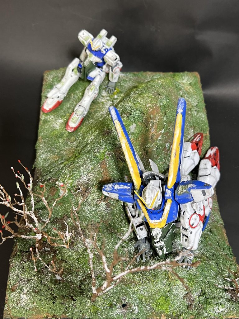 ジオラマ全景を上から。小さなジオラマベースで奥行きを出すためにあえてVガンダムはHGUCをチョイスして遠近感を強調しました。またVとV2の間に小高く山を作ることで、正面から見た時に2体の間が1度縁が切れるので遠近感が強調されるように意識して造形してみました。また大きな木は手前にだけ。奥に行くにつれ木の大きさも小さくしています。