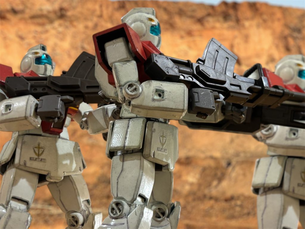 「いいな、主任務は威力偵察だ。状況がまずければすぐに後退するぞ。」　第１８MS中隊を指揮するディーン中尉は、スロットルレバーを握る掌が汗ばむのを感じながら、指揮下の８機に通信を送った。ミノフスキー粒子が戦闘濃度で散布されており、無線機に入る部下の返事もノイズが強い。　レバノンからダマスカスに抜ける山岳地帯を、地球連邦軍のMS隊が進軍を続けていた。パイロットは生きた心地がしない。MSも覆い隠す深い峡谷を進んでいくからだ。（上から襲われたらひとたまりもないが……。）先行して、ヘリや航空機が警戒に当たっているが、ミノフスキー粒子のせいでまともに連携が取れない。対空防御用に、180mmキャノン砲を担いだ機体を３機連れてきているが、もしガウやドダイの空爆を受ければ、あっという間に岩雪崩に生き埋めだ。（おまけに、アレクサンドリア方面は失敗したらしいじゃないか。）　レバノンのベイルートから上陸した部隊は、山岳地帯を超えて、まっすぐダマスカスを目指す。オデッサよろしく、空港を抑えて攻撃拠点にしたいのだ。ベルベット作戦の第１次攻撃の、宇宙からの電撃降下作戦で、ダマスカスはすでに制圧している。にもかかわらず、ディーン中尉がこんなにも緊張しているのは、この峡谷付近で残敵がゲリラ戦を展開していたからだ。　山岳地帯を行軍中は待ち受ける側にとっては非常に優位に戦いを進められる。本来ならば、いつものように遠距離からの砲撃と航空戦力による爆撃で薙ぎ払ってしまいたいところだが、アフリカ戦線は現地ゲリラの展開もある。ダマスカス付近は現地の人々の生活もある。いつもの物量戦だけでは如何ともし難いものがある。　開けたところで待ち伏せというのも、常套手段だ。だからこそ、エジプトはアレクサンドリア港の制圧が重要だった。アレクサンドリアの戦力を後ろ盾に、ガザからも陸上戦力を上陸させ、ヨルダンを通過して南からダマスカスに合流する予定だったのだ。　　しかし、アレクサンドリアは失敗した。何とか制圧はしたものの、ＭＳも洋上艦艇も、敵の反撃に大きな損害を受けた。敵の指揮官は名うての将だったらしい。退けた敵から昼夜に問わず反撃があるため、アレクサンドリアは拠点の維持に精一杯で、ガザに上陸する戦力を援護する余力がない。先の水陸両用MSの奇襲も危惧すれば、大それた作戦も取れず、結果、ガザの戦力はベイルートとアレクサンドリアに分散し、それぞれの戦力の後続に甘んじることになった。　ふと、集音マイクを通して遠雷のような響きが聞こえた。爆撃機のエンジン音に聞こえたが、まだ遠いようだ。（渓谷を抜けるとそこは敵陣だった、ってか。たのむ、せめてそこまでは行かせてくれよ。）とにかく、ここまで来たら肚を括るしかない。「間もなく渓谷を抜ける。接敵予定時間まで、あと１００秒。」◾️◾️◾️◾️◾️◾️◾️◾️◾️◾️◾️◾️◾️◾️◾️