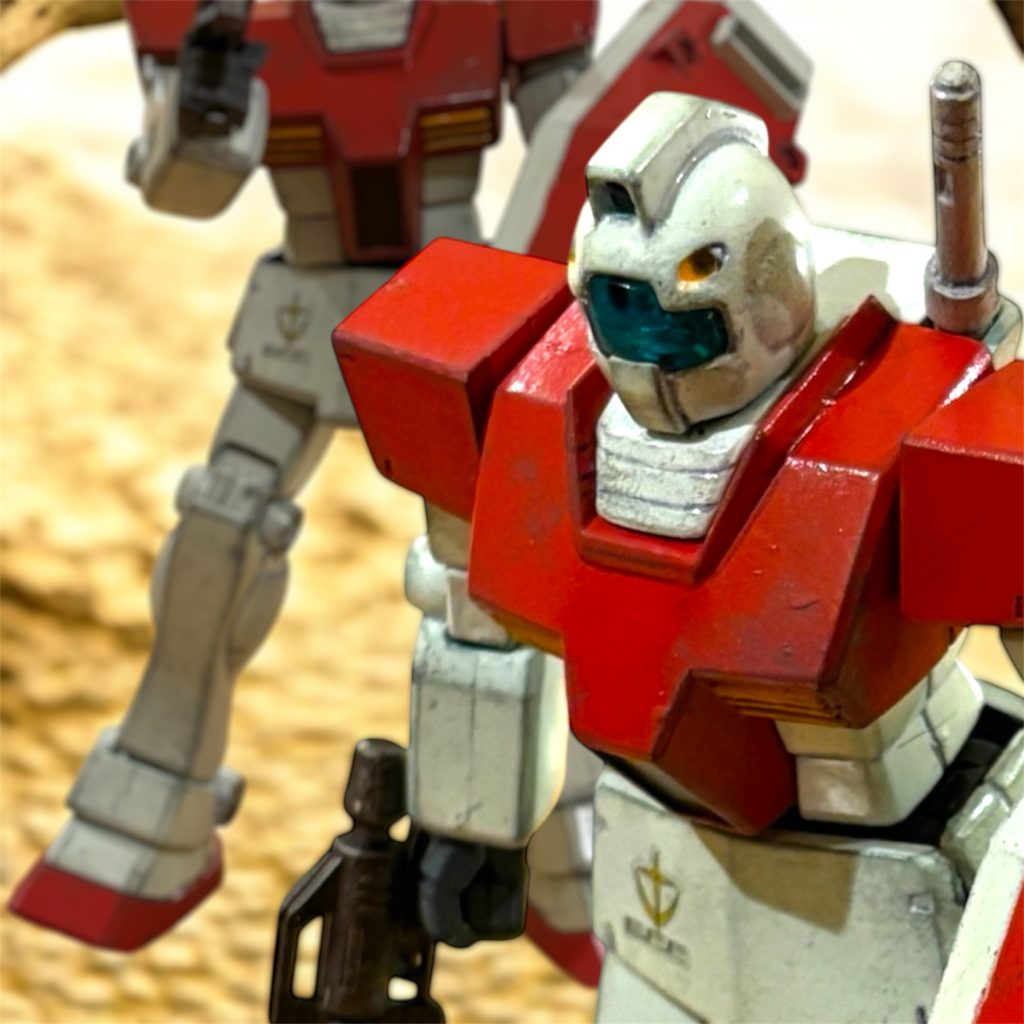 「見よう見まねでやってみたが、なるほどな。」　地上でも、各所のバーニアを強引にふかせば、短時間なら宇宙空間のような機動が取れる。ディーン中尉は、エースらしき敵機の機動を思い出しながら、コクピットで呟いていた。「しかし、６機も失った。ひどいやられようだ……。」戦闘の興奮が冷めてくると、自身の犯した失態に頭を抱えざるを得なかった。　十分に警戒をしていた。最初に宣言した通り”まずければすぐ撤退”した。しかし、半数以上部下を死なせた。（トルコやダマスカスからの増援は、あちらも予想しているはずだ。追撃はあるまいが……。）とにかく、敵戦力の情報を伝えなければならない。飛ぶように走る砂漠仕様のザクと、砂地から這い出して来るゲリラ戦術、そして……（赤い左腕のグフ……俺も、危なかった。）ビーム兵器を携行していたディーンのジムにも、まるで死ぬことを恐れていない、迷いのない凄まじい突撃だった。あのザクを真似てバーニアをふかして逃げなければ、きっと墜とされていた。「さしずめ”血濡れの左腕”というところか……。」　アフリカのジオンは強兵。　ああいう敵が、アフリカにはまだいるというのか。　ディーンは、峡谷を来た時と同じように、スロットルレバーを握る掌が汗ばんでいるのを感じていた。しかし今度は、レバーを握った指が開かない。「くそったれが……！」ディーンは思い切り、自身の唇の端を噛む。その痛みと、滴る血の生温かさが、まだ自分が生きていることを実感させた。 【#15 “RED SHOULDERs” / Nov.19.0079　fin.】 次回、#interlude Call sign