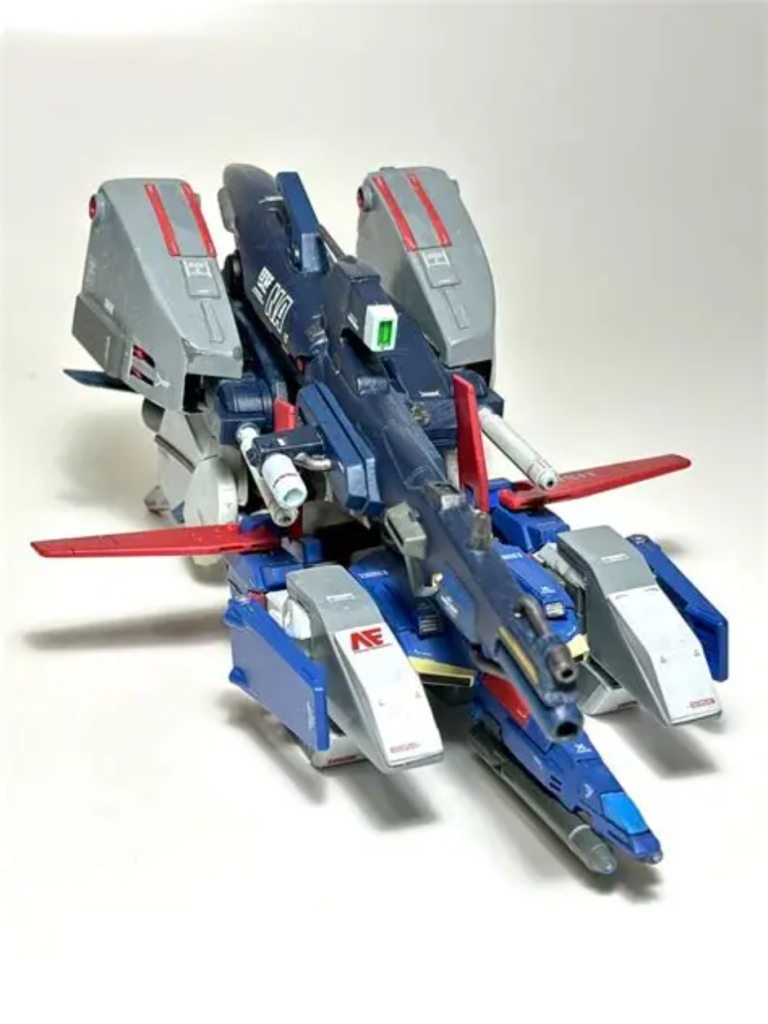 一番のポイントである、右側にオフセット装着されたハイパー・メガ・ランチャーはFA ZZ(フルアーマーZZガンダム)から拝借。設定画を見たところでは、手持ちできるタイプのようで、FA ZZのバックパックジョイントタイプのものとはかなり厚みが異なるよう。通常時はFA ZZに装備(?)させる予定のため、分厚いまま装着できるように、バックパックまわりを加工。前部・肩回り上下のミサイルポッドもプラ板箱組み。その他、サードパーティのディティールアップパーツやジャンクパーツで情報量アップ。いつものように水性ホビーカラーで筆塗り全塗装、水彩絵の具でスミ入れ、デカール貼ってつや消しトップコートで仕上げ。あえて、渋めの、少し暗いトリコロールに塗装。白は「HUG104 ディアクティブホワイト」、青は「XHUG13 ガンダムエアリアル(改修型)ブルー」、赤は「XHUG07 ダリルバルデレッド」、黄色は「XHUG06 デミトレーナー(チュチュ専用機)イエロー」。バックパックは「H42 ブルーグレー」。デカールはAEマークなどはガンダムデカール、その他大多数はグッドマークデカールのコーションマーク。