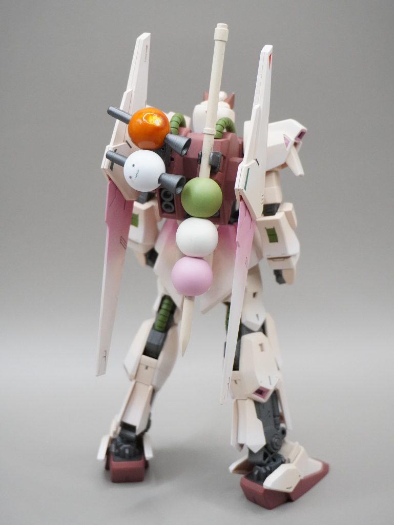 こだわりにして最大の特徴はバックパックに背負った「だんご装備」です。※わんちは犬・桜・だんご（和菓子）がモチーフのVtuberさんです①三色だんごメイスわんちの機体を作ろうと思ったときに最初に思いついた装備です。アクリルビーズの穴をピンバイスで広げて、プラ棒とプラパイプで作った串に突き刺しました。アクリルビーズかってえのよ。本体色と同じ色ではなくだんごっぽいカラーをここだけのために調色して塗装するのはちょっと面倒でしたが、おかげでだんごっぽくできたのでは？と手ごたえを感じています。②お団子ビット（うつろくん＆みたらし）わんちの運営さんである「うつろくん」とみたらし団子を模したビット武器です。メイスと同じくアクリルビーズに穴をあけてライフルの先とバーニアを差し込んでいます。みたらしは塗膜の乾かぬうちに触ってしまったので、逆にさらに派手に触ることで、みたらし団子の醤油だれがたまっている感じが出るように演出しました。 