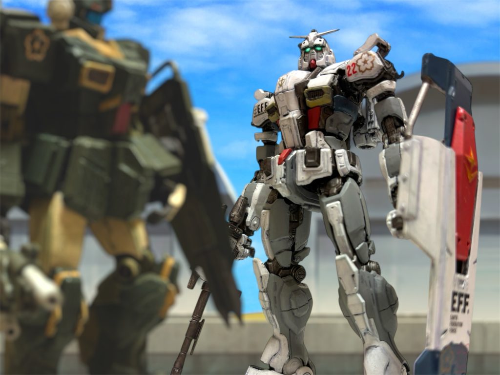 『派手にやったな、プレイボーイ。』 いつもの調子のイギーの声が、通信機から聞こえる。何のことだ、とヘントはとぼけて見せた。「プレイボーイはマーク曹長のコールサインだ。」そういえば、イギーが言い出したコールサインは、結局誰も使っていない。『やるようになったな。今晩あたり、二人で飲みに行け。』「明日は出撃だろう。真面目にやれ。」 受領したガンダムの試運転を兼ねて、イギーと模擬戦を行うために、機体をハンガーの外に出した。十分な慣熟訓練は行えそうもないが、それでも少しでも機体に慣れておきたい。 高性能機なら、ミヤギが受領するのが当然と思っていたが、今日受け取った機体で明日実戦という、過密すぎるスケジュールを考えれば、実戦での経験値が上回る自分がパイロットに指名されるのも頷ける。ミヤギの、ガンキャノンに慣れているから辞退したというのは本当だろう。ミヤギのために受領を急がせたブライトマンが、後方にどう言い訳をするのか、あるいはしたのか。多少気がかりではあるが、それは佐官の当然の仕事だ。(出力・推力は、陸戦型より確かに高い。だが、何だろう、この感じは……。) パワーだけではない。機体の動きや操作性が、より生物的というか、反応が良い気がする。(俺も、”ガンダム”の噂や伝説に騙されているのかな。) 中破した機体の改修機である”マスタング”は、どこか操作性が重く、スペックほどの性能を発揮していなかったとも思える。これまでの操作性へのストレスが、よく整備された新型機の反応を、より快適に感じさせているだけかもしれない。 左腕に携えたシールドが、やや重く感じるが、盾が大きいというのは気に入った点のひとつだ。幼い頃、21世紀の映画で見て憧れた愛国ヒーローも、盾が象徴的なキャラクターだった。