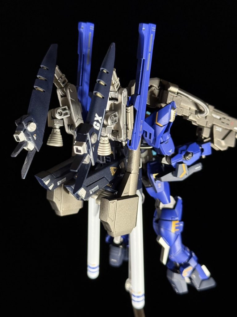後ろ。SDガンダムGXは思い出のゲームで、SDのキットが発売されたときHG準拠に改造しようと思っていました。技術不足でしばらくおいていたんですが、イモータルジャスティスの顔が似ている...ということに気付いたのでカスタム機として作成することにしました。最初はトルネードガンダム準拠のバックパックにしていたんですが、下側についてるスラスター(?)がちっちゃくてハッタリ効いてないな...と思ったのが運の尽き、下側にスラスター増設、プロペラントタンクも追加してクレイバズーカまで懸架させてしまい、結果として自立不能になりました。でもこういうごっちゃりカスタムってロマンですよね。年内にあと2機くらいは作りたいなあ...と思っています。