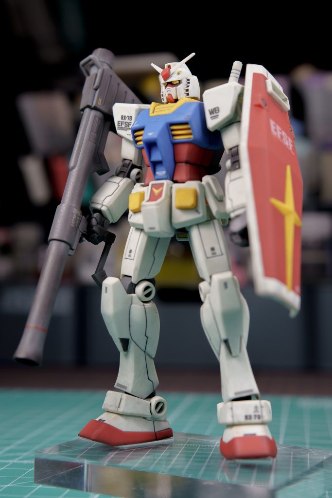 ディテールアップのスジ彫りは太ももと足の甲の部分に。ちょっと平面が大きくて寂しいと所に施してみたのですが、プラ板の上で何回か練習したとはいえ、立体的なパーツの上に刃を立てるのは緊張しますね。失敗できないと言うプレッシャーがすごかったです。これが全塗装する場合なら補修して消すことも可能だとは思うのですが、全塗装なんてまだまだまだ先の話なので、整形色仕上げ民としてはノー失敗をモットーに慎重に作業するしかありません。とは言え、何度か刃を滑らせてしまいましたけどね。(w 全体の仕上げは前回がちょっと汚しすぎた感があったので、ちょっと控えめに汚して完成としました。 汚しなしで仕上げたいなとも思ったのですが、ゲート処理の甘さや、タガネを滑らせた痕を誤魔化すのにも汚しは役に立っているので、当面はちょい汚しの仕上げを活用してこうとおもっています。今回の制作もたくさん経験値を積めてとても楽しかったですね。ただ、もうちょっと上手にできたかもしれない...と思うところもあるので、またいつか同じキットを買って再挑戦してみるのもおもしろいかもしれませんね。で、今回出来上がったガンダムは僕の持てる技術を全投入したイイ感じの出来栄えで気に入っているので、飾り棚のいい場所に置いておこうと思います。お読みいただきありがとうございました。また次回も覗きにきてください。