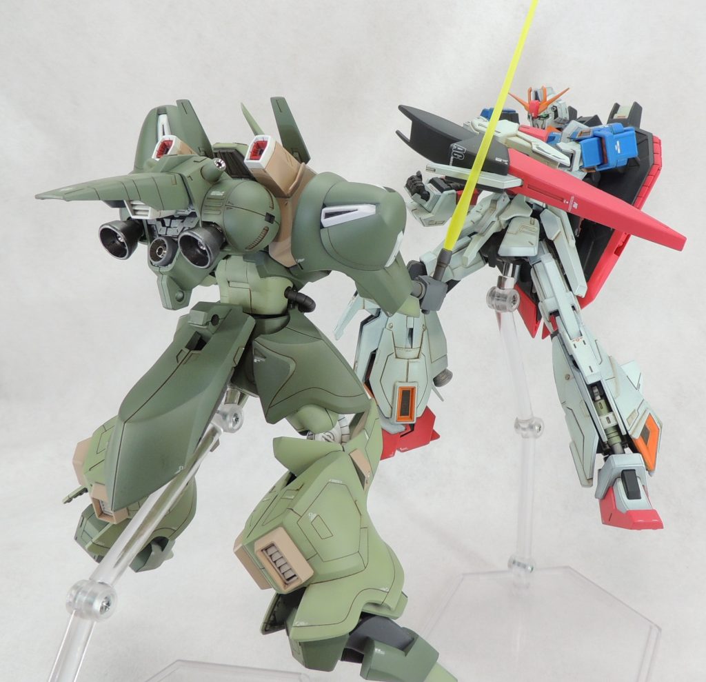 ■工作の詳細について［頭部］モノアイは、SPプレート(φ1.5mm)とHアイズ(φ1mm)に変更し、キットのモノアイ部品を一部削って取り付けました。頸部は背中側に肉抜き穴があるため、プラ板で塞いで整形しています。［腹部］腰部との接続用ボールジョイントを切り離し、腹部下面に積層プラ板を挟み込んで再接着しました。剛性・強度の向上のため、φ1.0mm真鍮線でボールジョインには軸打ちを行い、ガッチリと固定しています。この加工により、腹部を3.0mm程度延長し、無骨ながらスタイリッシュにプロポーションを変更しています。［バックパック］エバーグリーンのモールド入りプラ板等によりディティールを追加しました。塗装後、スラスター内にハイキューパーツ製の金属パイプを設置し、精密感をアップさせています。［リアスカート］内側にジャンクパーツを組み合わせて製作したプロペラントタンク2本を増設しました。［フィンガー・ランチャー］指の肉抜き穴を瞬間接着パテやプラ板で塞ぐとともに、指先にピンバイスで穴を開け、ハイキューパーツ製の金属部品ガンマズル(φ1.0mm)を接着しています。［その他ディティールの追加］全身にスジ彫りを入れたり、既存のモールドをBMCタガネで彫り込んだり、腕の4つ穴をピンバイスで開口したり、脚部の裾にエバーグリーンのモールド入りプラ板の細切りを貼り付けて”凹凸モールド”を再現したりと、目線の行きやすい箇所にモールドを追加しました。