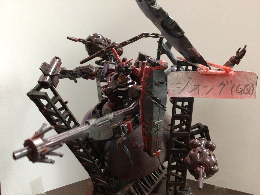 ジオングのスカート部分と赤いガンダムの上半身を接続し 赤いガンダムの腰部、脚部を赤いガンダムのバックパックに移植 メインカラーはグレー、時間がなかったので一部は成形色仕上げ ジオラマ本体には百均のトラスフレームセットとディスプレイスタンドの台座を使用 トラスフレームを組み上げた後ポージングさせたジオングをおき 背景には先に塗装しておいたジークアクスをセット ジークアクスは下半身を取り外し右手首を外しておいた 武器は付近のトラスフレームに接着し躍動感を出しました ジークアクス本体はライターで炙り焦がし表現を追加 ハンダゴテでビームサーベルで切られた描写を追加 赤いガンダムには通常のライフルに追加でガンダムファラクトのライフルを短くしたものを持たせた 最後に成形色と塗った部分の落差を埋めるため霧吹きでモンザレッド、ブラック、ニス、ホワイト、ダークグリーン、レッドの順で吹き付けました