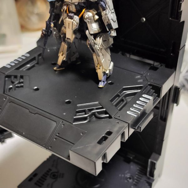 アーティファクトにも強い味方のディスプレイベースなんですが、HG MG 想定で豊富なオプションが構成されていて、飾るものがアーティファクトだとほとんど使えません。格納庫内周辺機材は、アーティファクト用に自作する必要のありそうです。ちょっと遊びで、アーガマの格納庫デッキのようなエレベーターを作ってみました。空母の格納庫からカタパルトデッキへ出撃機を移動させるエレベーターフロアのイメージです。ネオジム接続で支えを設けて、簡単つけ外し対応です。アーティファクトの重さなら、支えられそう。そういえばアーガマのカタパルトデッキって一つのデッキにレール一つでしたよね？　山田化学ディスプレイベースのカタパルトデッキはアーティファクトサイズだと、ひとつのデッキで交互に2機射出できそうです。（2枚目）