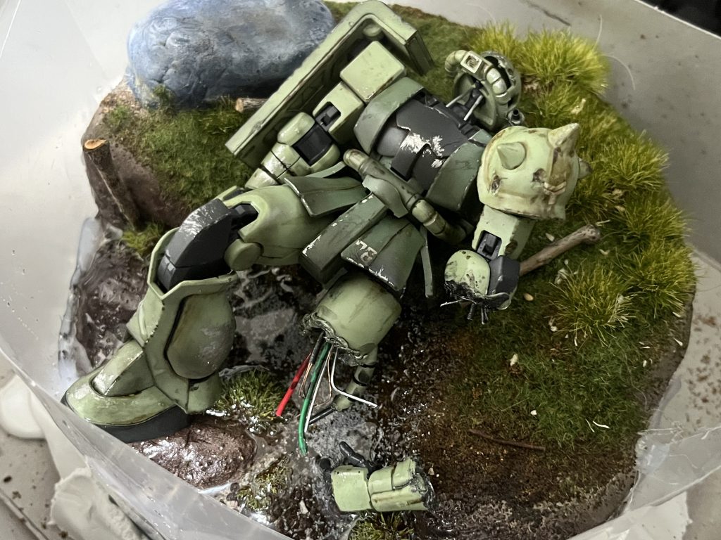 7/28 失敗 HG ザクⅡ前記のポリポッドボールで破壊表現をするならジオラマ等で背景がわかる前提じゃないと映えにくいと感じジオラマ製作を試してみました。川辺に打ち上げられたザクⅡをイメージして製作してみましたが仕上げに川の水を表現するために流したレジンが液漏れしてしまいジオラマを置いていた土台ごと硬化してしまったためやむなく廃棄となってしまいました…。 時間がある時に続きを書きますが、まとめ②に続きます…！