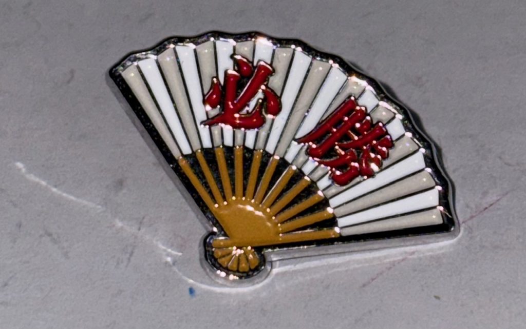 この「必勝」と書かれた扇子は実はファンネル兼サイコフレームであり、旧ザクのコクピットに搭載されたバイオセンサーとリンクして、サイコミュ兵器として使えるのだ。ナカさんの旧ザクはこれを使って敵のパイロットに「吐け～」と長時間プレッシャーを与え戦意喪失させたり、敵の攻撃をはじくフォースバリアを発生させたりする事も可能。なおこの「吐け～」はニュータイプや強化人間にも効果抜群らしい。なお扇子は打撃用の武器にもなる。※この扇子のピンバッジは「あぶない刑事DVDコレクション」の付録である。サイズがちょうどあっていたのでそのまま装備させた。