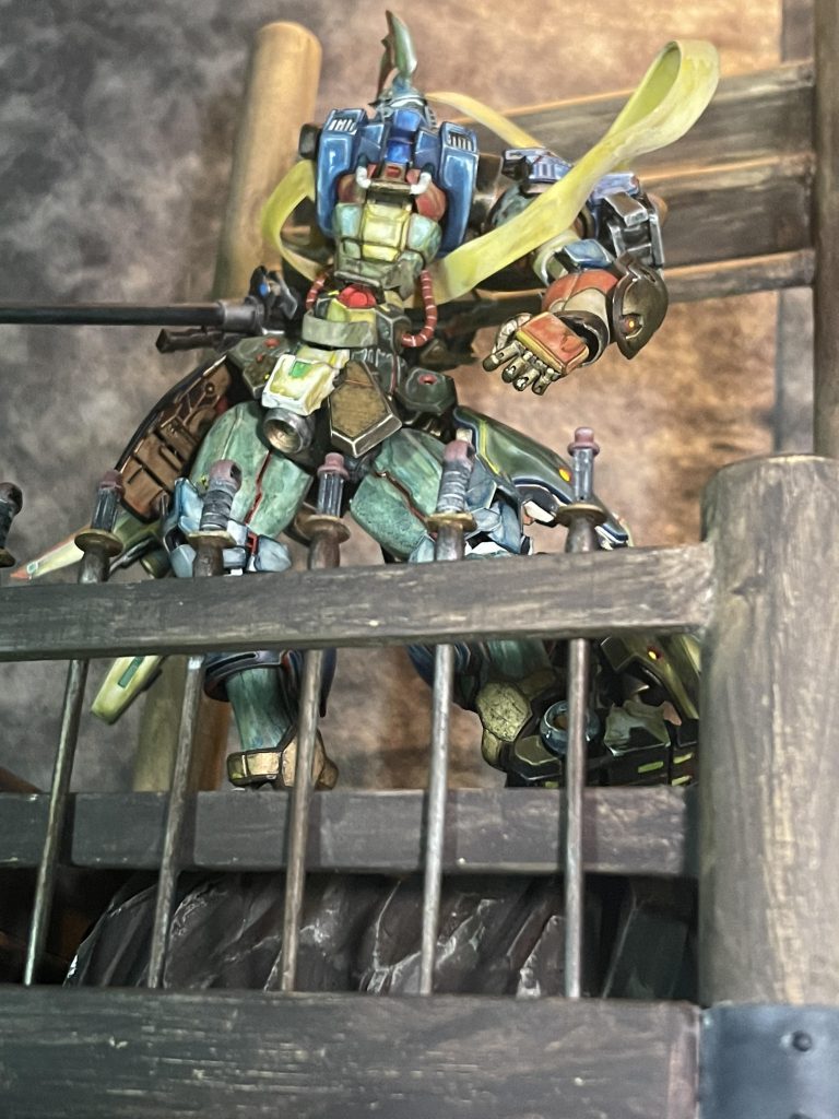 あおりショット。実際の仁王像の囲いの柵部分には剣が刺さっているのですが、ガンダム作品で剣といえばビームサーベルなので普段作らないで余っているビームサーベルを、今回大量に消化する事ができました。柵の部分は何を使おうかと考えてた時に『あー、ビームサーベルはこの時の為に捨てないで取ってあったのか』と都合良く解釈しました。持ち手部分はハロの腕や脚を使用し接続軸も持ち手に見立て製作しました。