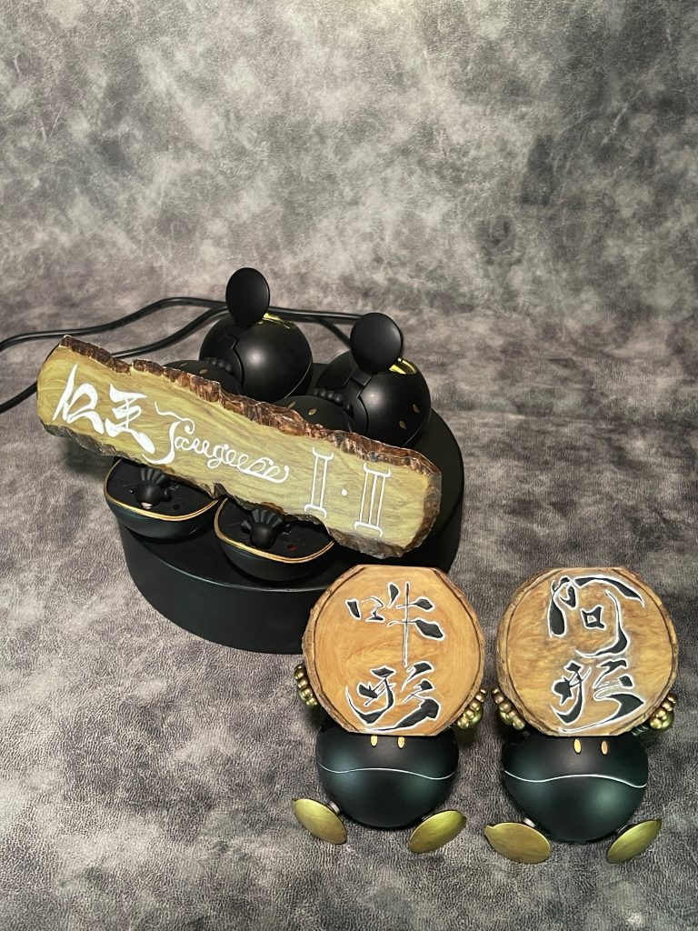 後ろ側にある題目の奥にいるハロの中にスポットライトを仕込んであり裸眼で観る時に夜の寺の門にいる仁王像のイメージになる様にしています。題目と阿吽の文字は、一度半紙に筆書きしてから良さげなヤツを選んで見ながら鉛筆でプラ板に書き、掘り込みを入れてから色を入れていきました。