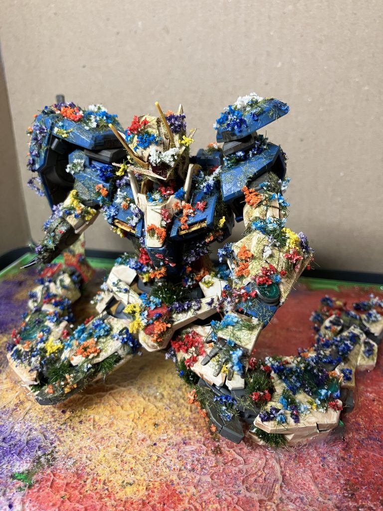 本体にはKATOの草をまぶして、ミニチュアの花畑の花を接着しています。白色を購入して、水性マジックで各種色を塗りました。土台は1.5ミリのプラ板とL字プラ材で作りました。KATOの草をまぶして、KATOの花?パウダー?をまぶして、KATOのリアリスティックウォーター?を注ぎました。水表現がうまくできなかったのが課題です。