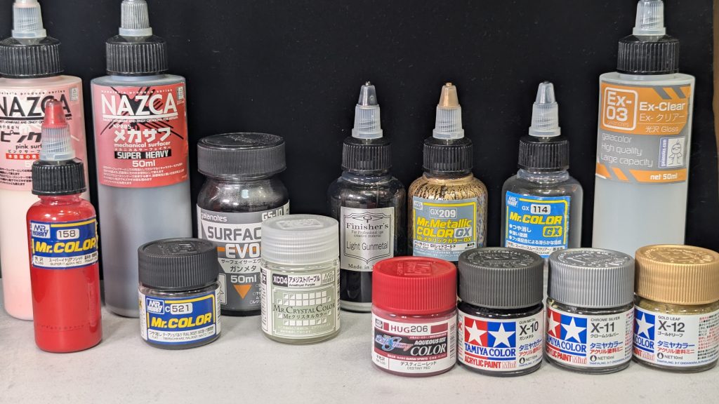 塗装レシピは以下のとおりです。下地(外装):ガイア メカサフ スーパーヘビー下地(フレーム):ガイア ガンメタ下地(塗り分け):ガイア メカサフ ピンクフレーム:クレオス アメジストパープルボディ黒:クレオス テーアシュバルツボディ赤:クレオス イタリアンレッドアクセント①金:クレオス レッドゴールドアクセント②銀:フィニッシャーズ ライトガンメタルトップコート:クレオス スーパースムースクリアーボディ黒で採用したテーアシュバルツですが、かすかに茶色が混じった黒で、全体的に赤み(紫、茶、金)を感じる配色にしています。また、筆塗りで使用した水性塗料は下記です。タミヤ ガンメタタミヤ クロームシルバータミヤ ゴールドリーフクレオス デスティニーレッド筆塗り技術を高めたく色々な塗料を使ってみましたが、メタリックに関して言えばタミヤのアクリル塗料がもっとも使いやすいと感じています。また、隠蔽力の低い「赤」に関して、色々試したところ今回使ったデスティニーレッドが使い心地が良かったです。若干、彩度が低いのでイタリアンレッドとはそれほどマッチしませんでしたが、トップコートでつや消しにして50cmくらい離れれば気になりません(笑レッドチップには丁度良いと感じました。