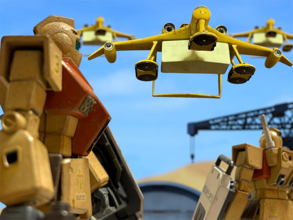 「来たな。」 空を割くエンジン音を聞く。見上げた先、ミデアの編隊が見え、ラッキー・ブライトマン少佐は思わず呟いた。 間に合った。この装備を最短の空路で受け取るために、ルトバ制圧を急いだのだ。「……で、曹長はそれでいいんだな?」はい、と、短く明確に答える女傑に、ブライトマンはやれやれとため息をついた。「まあ、合理的な提案ではあるがね。でも、これ、お前さんが単に、あいつを心配しているだけだろうが。」「自分の提案には、作戦遂行に向けた合理的判断以外の他意はありません。」「当たり前だ。そのせいで今から上への言い訳を考える俺の身にもなれ。なんで若い奴らの仲人みたいな感覚でやらにゃあならんのだ。ここは軍隊だぞ。」口に出した内容とは裏腹に、楽しそうな口調だ。「ですので、自分には合理的判断以外の……」「分かった分かった。ほら、命令書を書き換えた。お前があいつのとこまで持っていけ。」茶封筒を手渡すと、目の前のウェーブ(女性仕官)は、え、とたじろいだ。「知ってるんだぞ、お前ら、ルトバに入ってから一言も口を聞いてないだろ。いいから行け。復命は要らん。」爽やかに返事と敬礼をしてウェーブが去った後、ブライトマンはもう一度、やれやれとため息をついた。「我らがジャンヌ・ダルクに、オトコがいちゃあならんだろう。」〜〜〜〜〜〜〜〜〜〜〜〜〜〜〜