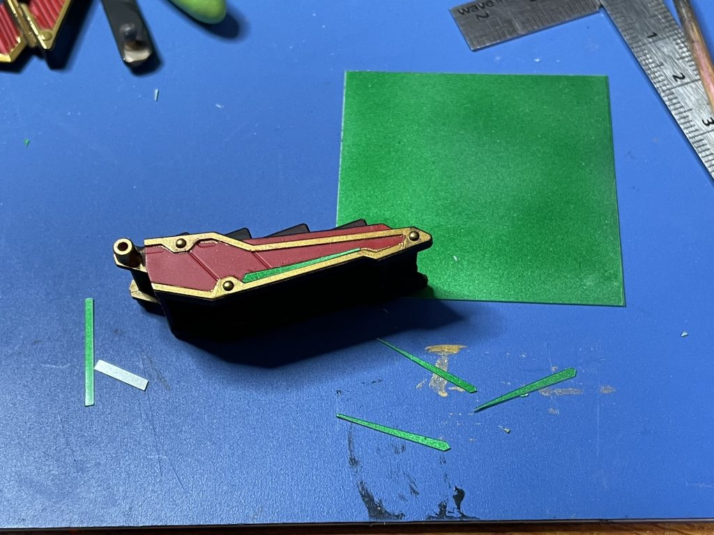 全身のグリーン箇所は裏をグリーンに塗った0.2mmクリアプラ板を切り出して貼り付けてます。接着にはハイグレード模型用セメダインを使いました。当初はラピーテープを使うつもりでテープも購入しましたが、蛍光で光らせたくてこの方式に切り替えました。ただし、この方式は三次元曲面には使えないので鞘の一部はラピーテープを貼ってます。いわば、ジェネリック3Dメタリックシールですね。本家ほどは光らないけど。反射面をラピーテープやハセガワのミラーフィニッシュとかにしたらもっと光るかも。