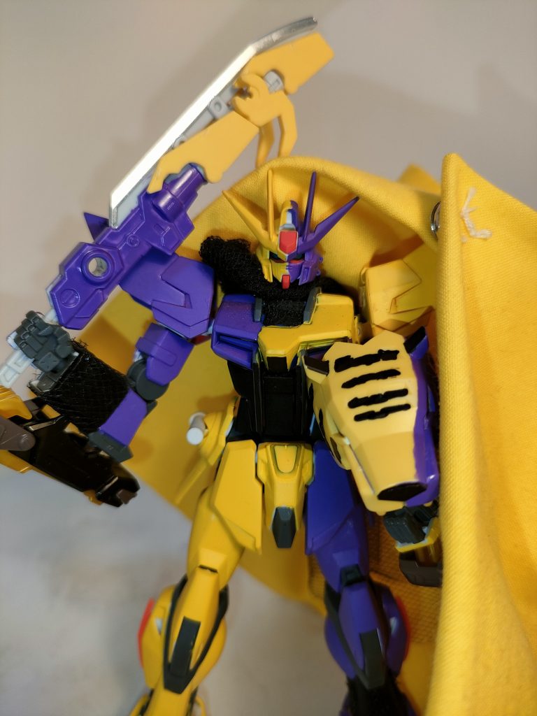 　ちなみに筆塗りで再全塗装しており、黄色側にはクリアイエローを上塗りさて、紫側にはメタルバイオレットを上塗り。黒も改めて塗り直し、再び艶消しトップコートを塗りました。　頭部はHGブリッツに変更。右肩と二の腕上部、サイドアーマー&ビームサーベルをプレバンのダガーLのものに変更しております。　ちなみにもうコイツの正体に気付いてるでしょうが…。