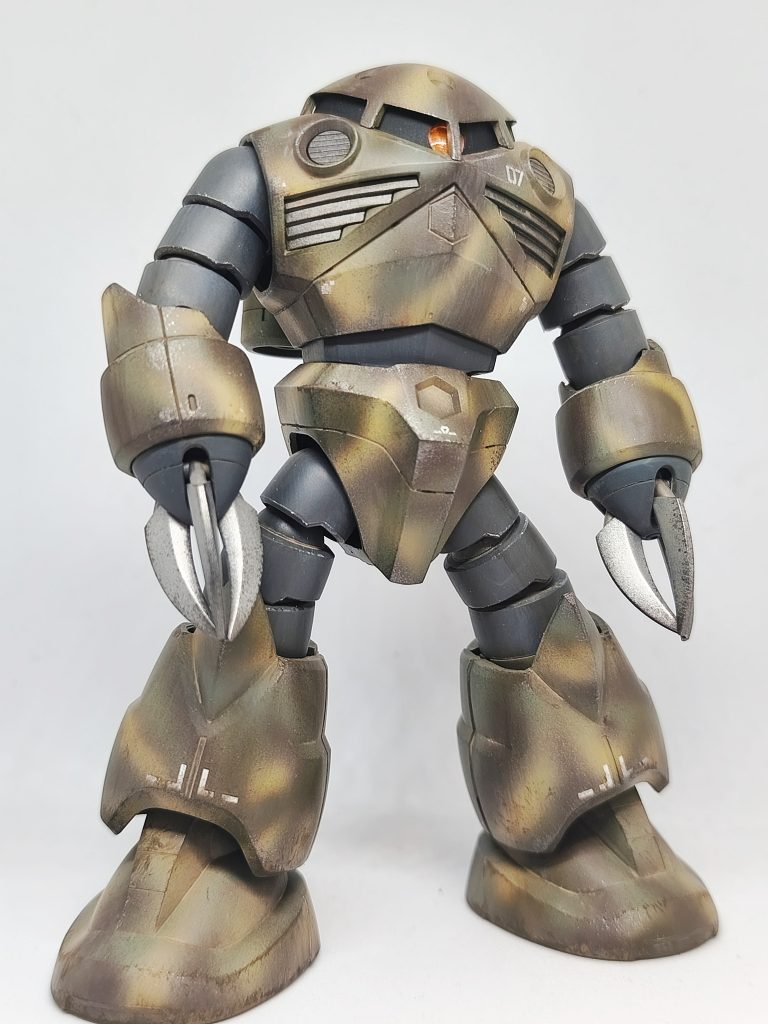 全体像ウッドブラウンオリーブドラブザクの濃い方のグリーンサンドイエローの4色で迷彩塗装。クロー部を中心に全体的に軽く焼鉄色足元を中心にMr.ウェザリングペイントのウオッシュアンバーミディアムマッドファインダストでウェザリングしています。Mr.ウェザリングカラーのグレイッシュブラウングランドブラウンで雨だれも意識しながらウオッシュとスミ入れを兼ねて。マルチホワイトにグレイッシュブラウンを混ぜたもので塩汚れ垂れもつけてみました。最後にモノアイとコクピットエッジ部をウェザリングライナーホワイトでハイライトを入れています。