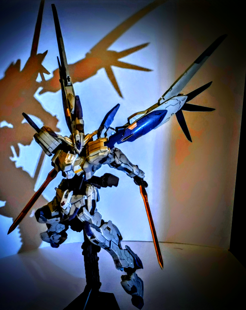 こちら前回製作したものです。前回の製作では３つの点を意識しました。1つ目はシルエットを大きく変更し、人型としての立ち姿を強調すること。2つ目はディティールを追加し、全体の情報量を増やすこと。３つ目はスラスターをより羽のように見せるため、プラ版を用いて調整を施したことです。これら三点により、本機がアニメ本編で持っていた「異質」さを再現することを意図しました。 