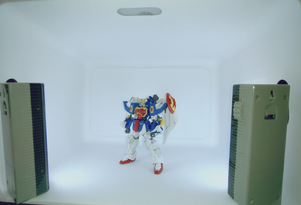 撮影環境と雑談。撮影環境はダイソー製です。ダイソーのスクエア収納ボックスを横倒しにして、同じくダイソーのライトを左右と上から当てています。この記事のトップ画像です。正直光量がまだ足りないのか、オープンスペースで撮った2枚目の画像の方が明るいです。おそらくは天井照明の明るさ不足かな、と思います。ただ、今回はあえて暗い方の写真を選んでトップに持ってきました。そちらの方が写真として自然に撮られたものだからです。最近はAI技術が発展しているので、本物のプラモデルのような画像を作ることが出来るようになってきています。作成途中の風景も作れてしまいます。また、1から生成しなくても、今回のように背景をきれいに消したり、リタッチしたり出来ますし、そもそもスマホ自体が撮影時に勝手に色味を変えていたりもします。正直何も信じられない状態ですが、個人的にはせめて加工の少ない素に近い状態で撮ったものを出せればな……とそんな思いで1枚目を選びました。他の方にこの思想を押し付ける気持ちはありませんが、この先写真メインのコンテストとかはどうなっちゃうのかな……と若干不安な気持ちです。