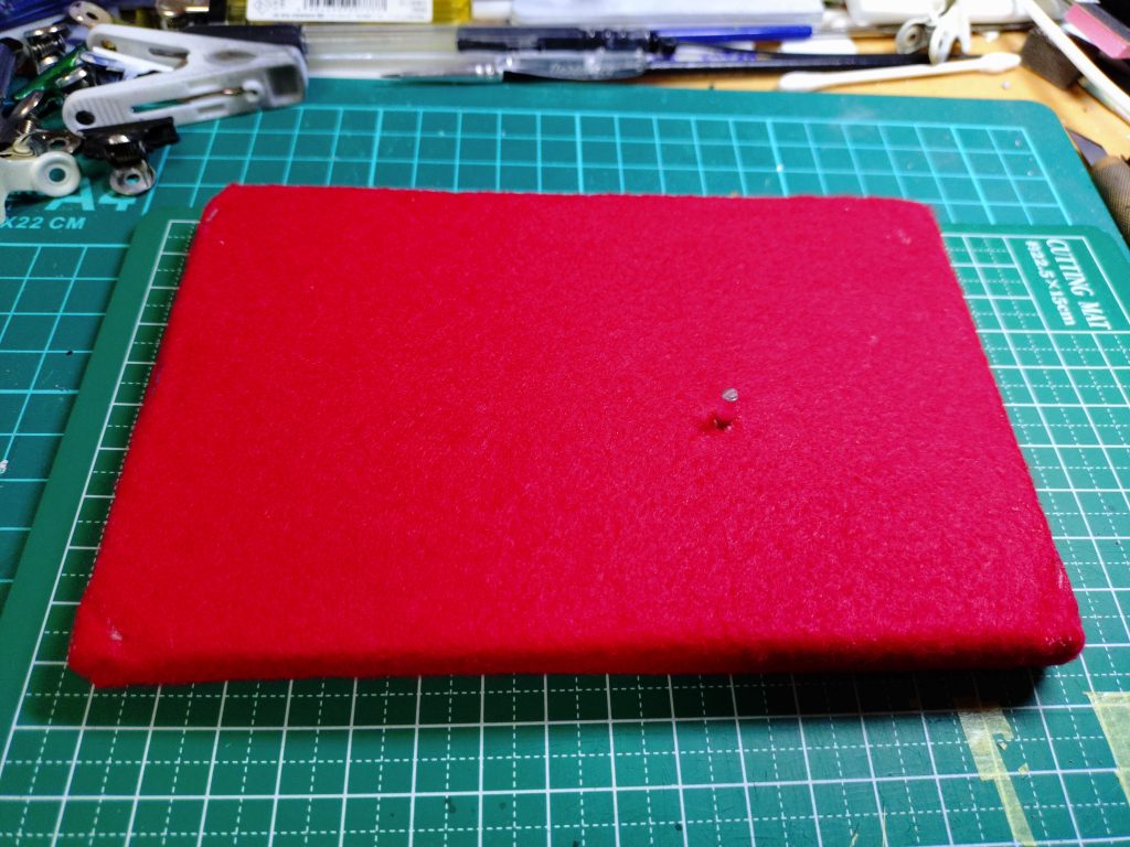 コルクボードに赤のキルトを張って足の軸打ちをして完成