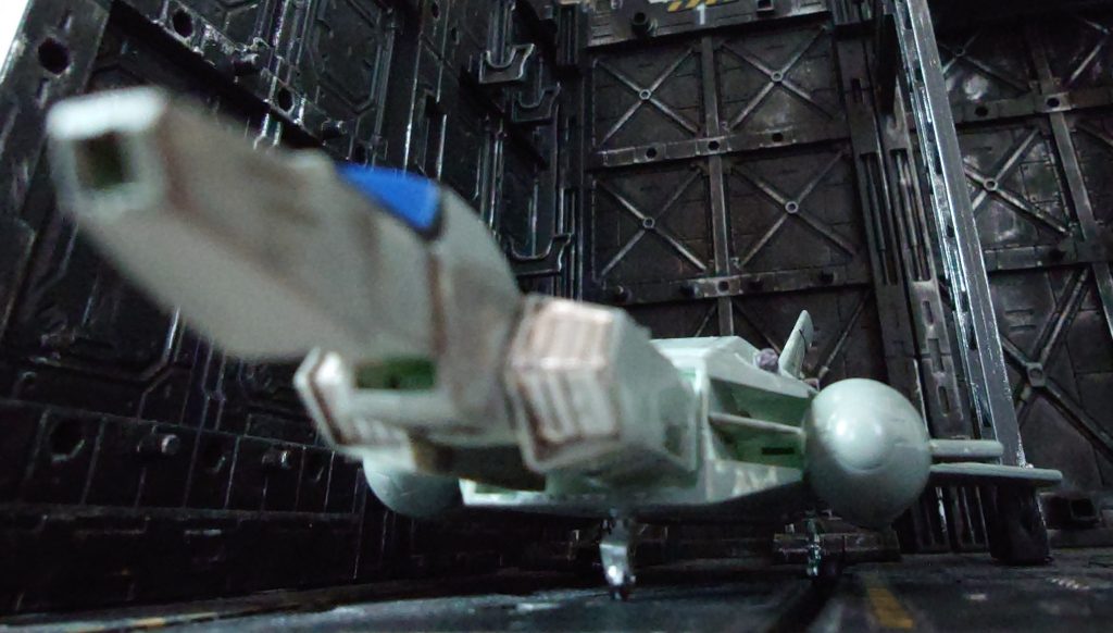 　ﾒｲﾄﾘｸｽ、ﾊﾞｰｸﾞﾚﾝ、ﾍﾞﾆｰら三人はMSデッキでコアブースターを眺めていた　ﾊﾞｰｸﾞﾚﾝ「ちょっと！連邦軍でも最強と名高いアグレッサー部隊の302教導大隊がなんで来てんのよ！しかもコアブースターなんてまだ連邦軍全体でも１０機も配備されてないのよ！」　ﾒｲﾄﾘｸｽ「長く軍人やってると、貸しも伝手も色々できるんだよ　そんなことより出迎えに行くぞ」と手すりを乗り越え、無重力の中、緩やかに自然落下しつつコアブースターのそばに降りた　コアブースターのキャノピーが開き、黄色いノーマルスーツを着た人物がﾒｲﾄﾘｸｽらに視線を向け、挨拶をするかのように右手を掲げた　ﾒｲﾄﾘｸｽ「中佐！久しぶりだな！」　ﾊﾞｰｸﾞﾚﾝ「え？知り合いなの？」　パイロットが降りてきて、ヘルメットを外した　口ひげをはやした黒人の男が破顔一笑！　ﾓｰﾘｰ「よう！ブロゥ（兄弟）！水くせぇじゃねーか　相変わらず暴れてるか？」　ﾒｲﾄﾘｸｽ「アクセル、久しぶりだな　相棒は相変わらずかい？」とﾓｰﾘｰが抜く手も見せずに脇のホルスターから鈍く輝く一丁の拳銃を手にしていた　ﾓｰﾘｰ「お前さんが用意してくれたルナチタニウムから削り出したブローニ◯グハイパワーは最高だぜ」とウインク　ﾓｰﾘｰ「そろそろそちらの美人さんを紹介してくれよ」　ﾒｲﾄﾘｸｽ「ああ、こちらは302教導大隊のアクセル・モーリー中佐だ　俺のブロゥでもある　アクセル、連邦軍参謀本部直轄のガンマフォース所属のキャサリン・バーグレン少佐だ　今回の作戦の監察役だ」とﾓｰﾘｰがヒュウと口笛を吹いた　ﾓｰﾘｰ「おっかねぇ、漏らしちまいそうだ　バーグレン少佐、よろしく　アクセル・モーリー中佐だ」と敬礼した　ﾊﾞｰｸﾞﾚﾝ「は！中佐！よろしくお願いします！」とにこやかに答礼する　ﾍﾞﾆｰ「自分はベニー・ウォーカー中尉であります！」敬礼するﾍﾞﾆｰ　ﾓｰﾘｰ「ん？おぅ、よろしくな　角のないガンダムがイアンので、同系色のジムが君のか　グレーのジムがバーグレン少佐のか　俺が呼ばれたってことは…ジオンの本拠地に殴り込みか？」　ﾒｲﾄﾘｸｽ「まあな　詳細はまだバーグレンが教えてくれないんだよ」　ﾊﾞｰｸﾞﾚﾝ「予定宙域に着かないと開封出来ないので」とニコリ　ﾒｲﾄﾘｸｽ「な！おっかねぇだろ？」ニヤリとするﾒｲﾄﾘｸｽとﾓｰﾘｰ　ﾍﾞﾆｰ「その拳銃、旧世紀のですよね　博物館で見たことありますよ　ルナチタニウムなんて素材、どうやって調達したんですか、少佐？」　ﾒｲﾄﾘｸｽ「良い軍人には色々伝手が出来るんだよ」　ﾓｰﾘｰ「構造は博物館のと変わらないが、ルナチタニウムだからすげぇ頑丈でな　弾丸も強装弾でアーマーピアシング弾を撃ち出すんだ　パイロットには心強いサバイバルガンだよ」　ﾊﾞｰｸﾞﾚﾝ「お二人はどういう繋がり？」　ﾓｰﾘｰ「パイロットのサバイバル訓練で少佐にしごかれてな　色々話しているうちに共通の趣味があってな」　ﾍﾞﾆｰ「ガンマニアってことっすか？」　ﾒｲﾄﾘｸｽ「ベニー、言葉を選べ　自分達の命を託す道具に一家言あるだけさ」と抜く手も見せずにﾒｲﾄﾘｸｽの手の中にはクロームシルバーに輝くコ◯トガバメントが握られていた　ﾍﾞﾆｰ「いいなぁ　それもルナチタニウム使ってるんでしょ　俺も欲しいなぁ」　ﾊﾞｰｸﾞﾚﾝ「はいはい　趣味の話はまた今度！会議室に行くわよ！」と歩き去ってしまった　ﾓｰﾘｰ「真面目だね　まあ、俺も仕事に来たからな」　ﾒｲﾄﾘｸｽ「行くとしますか」と三人もMSデッキを後にした…　（続く）